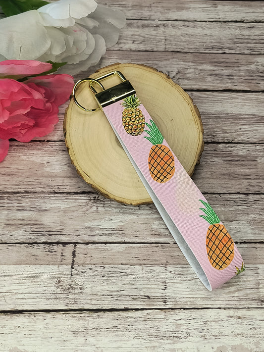Pineapple faux leather wristlet in pink featuring vibrant pineapple patterns and a gold keyring